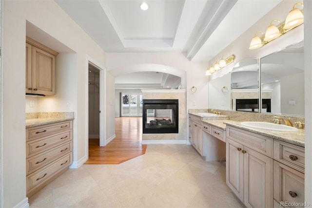 4800 E Cedar Ave, Denver, CO 80246 - full bathroom with a multi sided fireplace, a raised ceiling, double vanity, baseboards, and recessed lighting