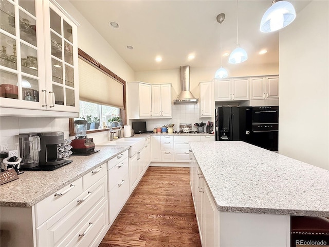 185 Wildrose Ct, Woodland Park, CO 80863 - kitchen featuring wall chimney range hood, wood finished floors, black fridge, decorative backsplash, and a kitchen island