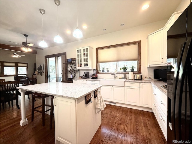 185 Wildrose Ct, Woodland Park, CO 80863 - kitchen with black fridge with ice dispenser, a kitchen island, healthy amount of natural light, light stone countertops, and recessed lighting