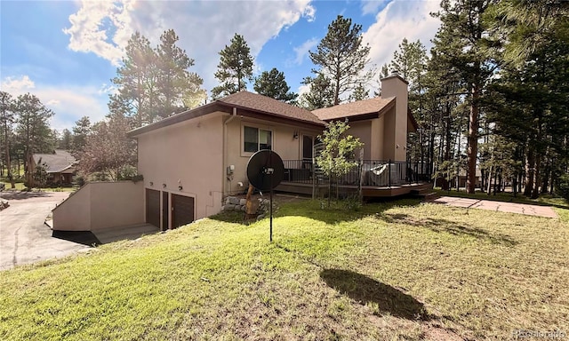 185 Wildrose Ct, Woodland Park, CO 80863 - rear view of house featuring a garage, stucco siding, a deck, and a lawn