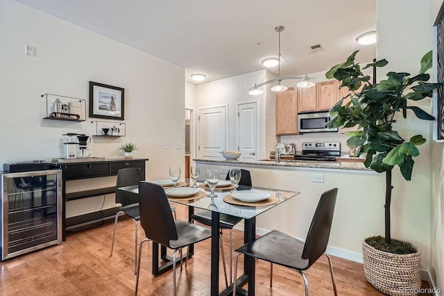 dining area with beverage cooler and light wood-style floors