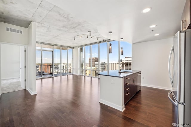 kitchen with floor to ceiling windows, dark wood-type flooring, an island with sink, and stainless steel appliances