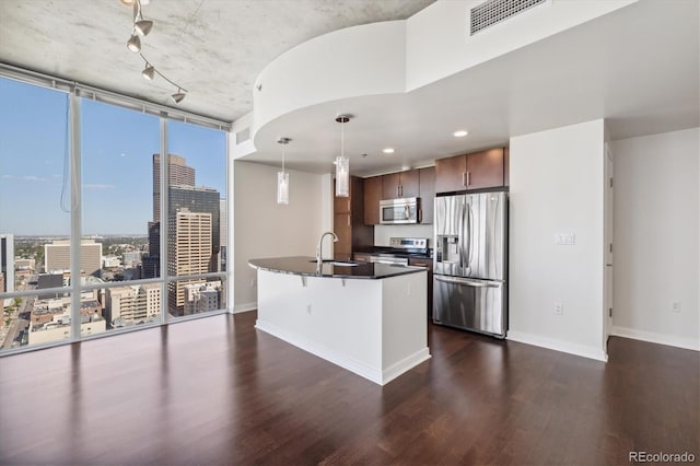 kitchen with a kitchen island with sink, dark hardwood / wood-style flooring, stainless steel appliances, and hanging light fixtures