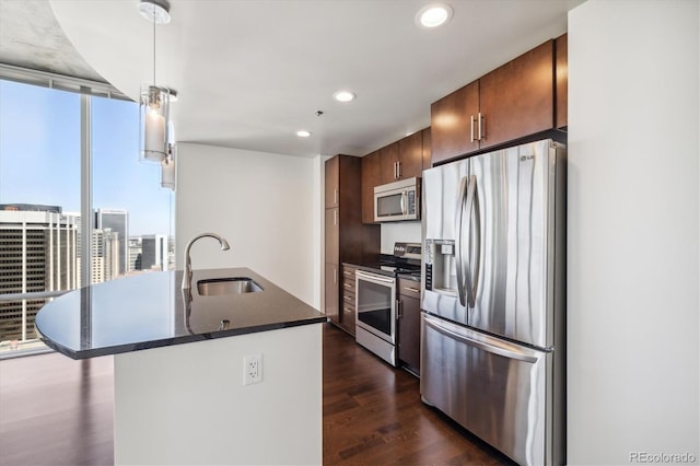 kitchen featuring recessed lighting, dark countertops, dark wood finished floors, stainless steel appliances, and a sink