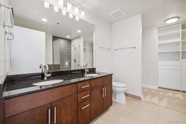 bathroom with tile patterned flooring, vanity, toilet, and a tile shower