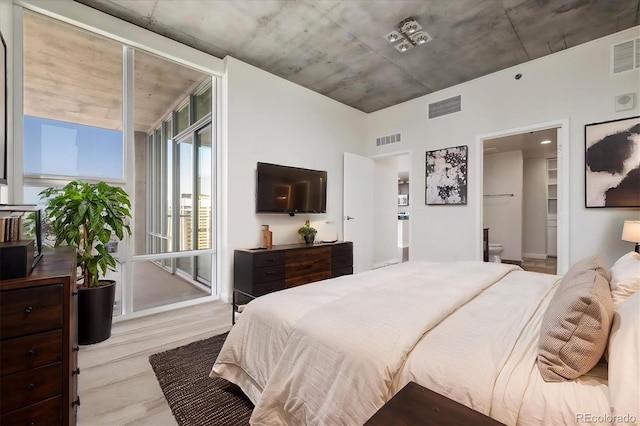 bedroom featuring connected bathroom and light hardwood / wood-style flooring