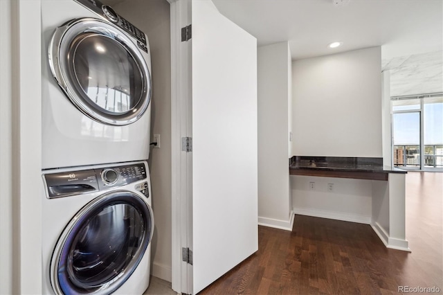 laundry area featuring baseboards, laundry area, stacked washer / drying machine, recessed lighting, and wood finished floors