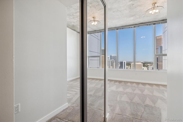 carpeted spare room featuring a chandelier, a city view, and baseboards