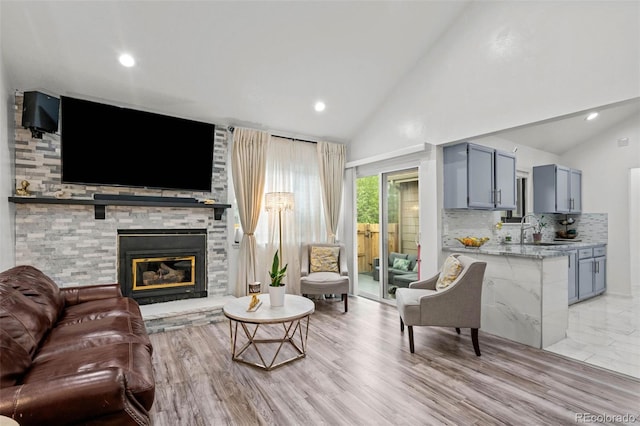 living area with high vaulted ceiling, recessed lighting, and a stone fireplace