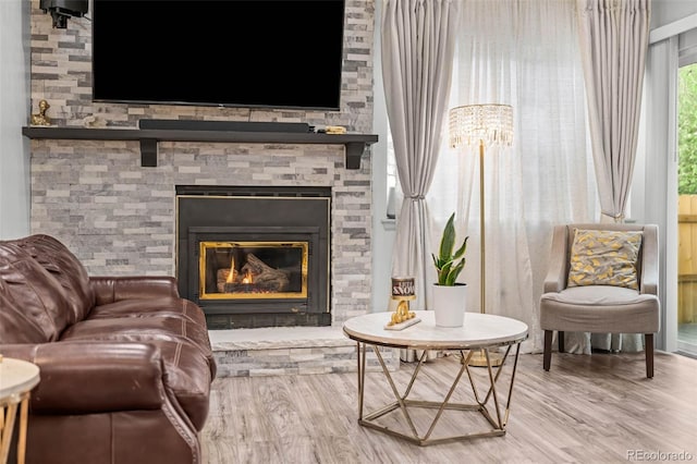 living area with a stone fireplace and wood finished floors