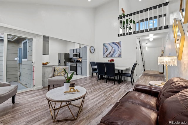 living room featuring baseboards, a high ceiling, and light wood-type flooring