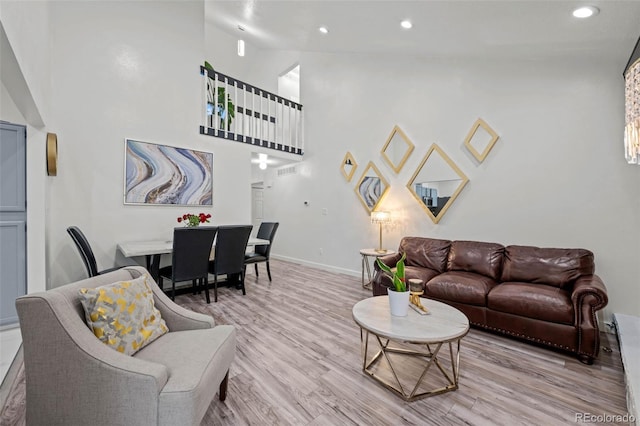 living room with recessed lighting, baseboards, a towering ceiling, and wood finished floors