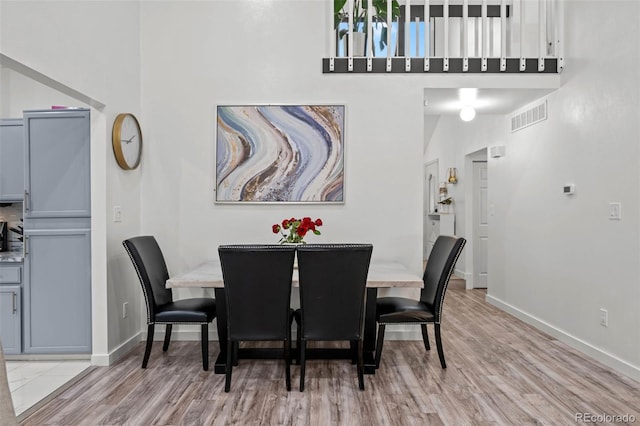 dining space featuring baseboards, visible vents, and a towering ceiling