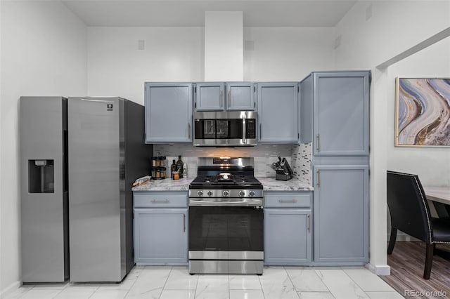kitchen featuring light stone counters, marble finish floor, gray cabinetry, and stainless steel appliances
