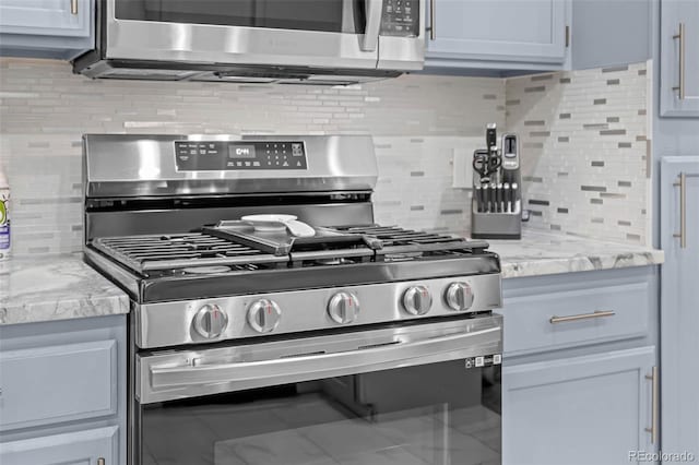 interior details featuring light stone countertops, appliances with stainless steel finishes, and decorative backsplash
