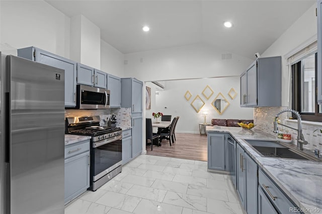 kitchen featuring gray cabinetry, appliances with stainless steel finishes, a sink, and lofted ceiling