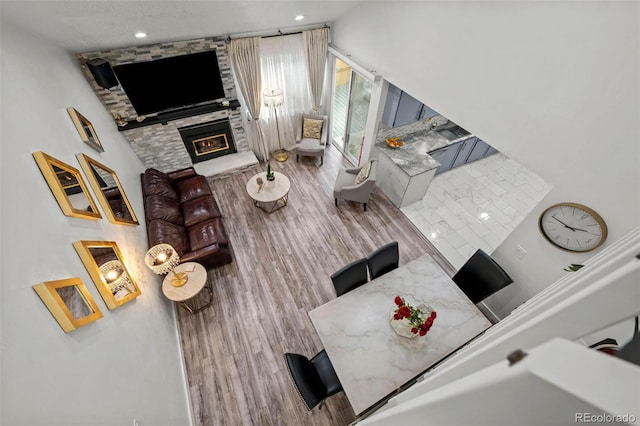 living area with a stone fireplace, recessed lighting, and wood finished floors