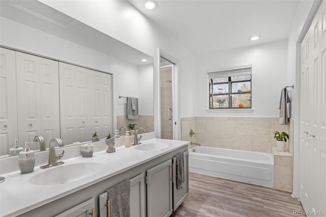bathroom with double vanity, a sink, a bath, and wood finished floors