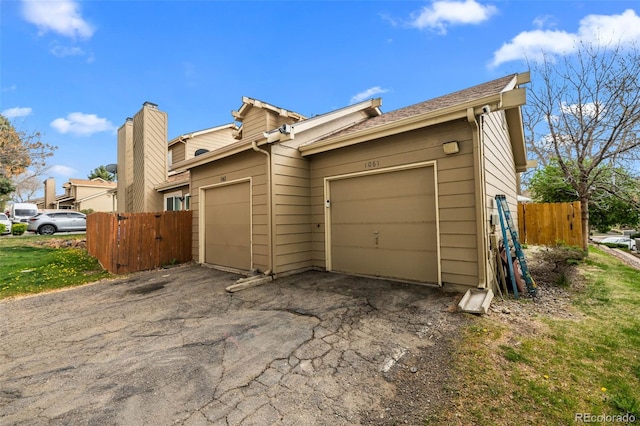 exterior space with a garage, aphalt driveway, and fence