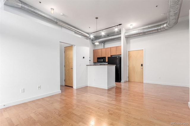 7700 E 29th Ave Unit 405, Denver, CO 80238 - unfurnished living room featuring a towering ceiling, light wood-style floors, baseboards, and rail lighting