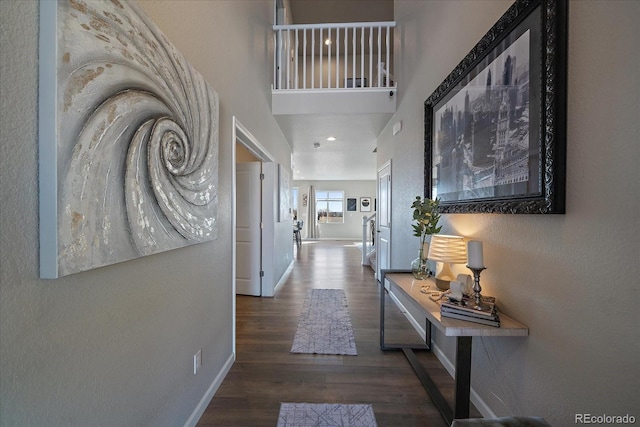 hallway with baseboards, a high ceiling, and wood finished floors