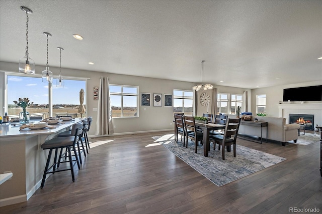 dining area featuring a glass covered fireplace, a textured ceiling, and dark wood-style floors