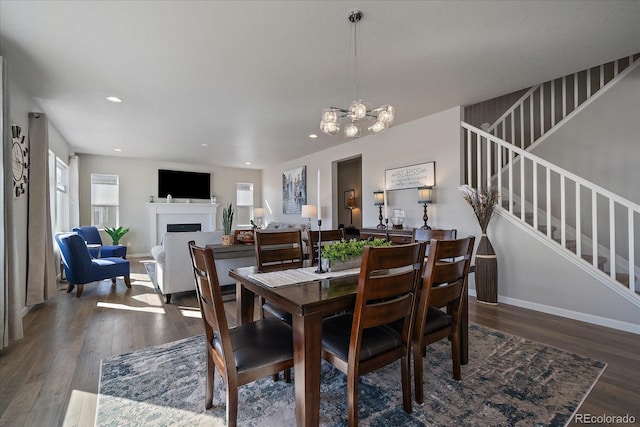 dining space featuring stairway, wood finished floors, baseboards, a fireplace, and recessed lighting