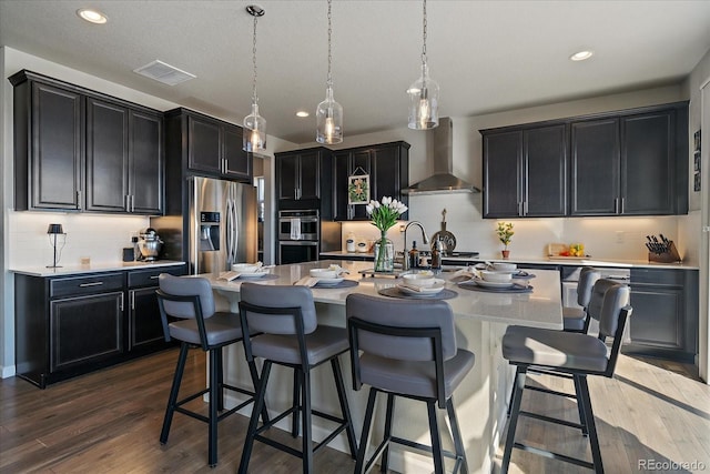 kitchen with visible vents, dark cabinets, stainless steel appliances, wall chimney exhaust hood, and dark wood-style flooring