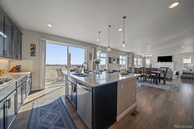 kitchen with an island with sink, hardwood / wood-style flooring, a sink, appliances with stainless steel finishes, and light countertops