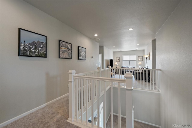 hall with baseboards, an upstairs landing, carpet flooring, recessed lighting, and a textured ceiling