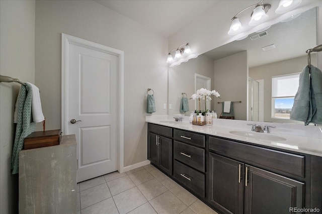 bathroom featuring tile patterned floors, visible vents, double vanity, and a sink