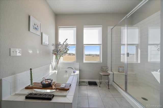 full bathroom featuring tile patterned floors, baseboards, a stall shower, and a bath