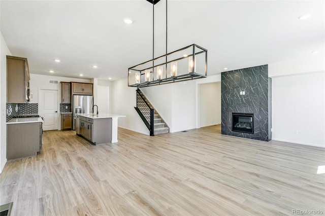 4451 Soapberry Pl, Castle Rock, CO 80108 - unfurnished living room featuring light wood-style floors, stairs, a fireplace, recessed lighting, and a chandelier