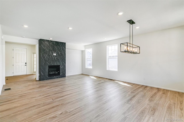 4451 Soapberry Pl, Castle Rock, CO 80108 - unfurnished living room with recessed lighting, light wood-style floors, a fireplace, and a chandelier