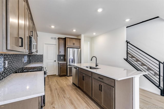 4451 Soapberry Pl, Castle Rock, CO 80108 - kitchen featuring stainless steel appliances, light wood-style floors, decorative backsplash, a kitchen island with sink, and recessed lighting