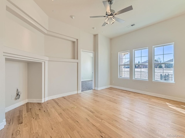 interior space featuring a ceiling fan, baseboards, visible vents, and light wood finished floors