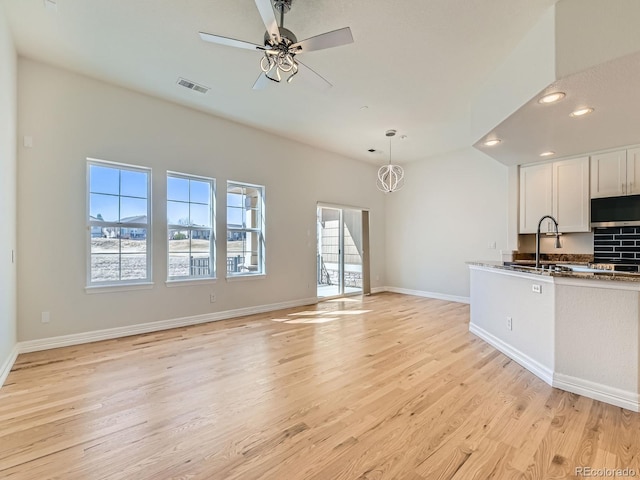 kitchen with visible vents, light wood-style flooring, a ceiling fan, white cabinetry, and baseboards