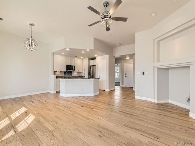 unfurnished living room featuring ceiling fan with notable chandelier, recessed lighting, light wood-style flooring, and baseboards