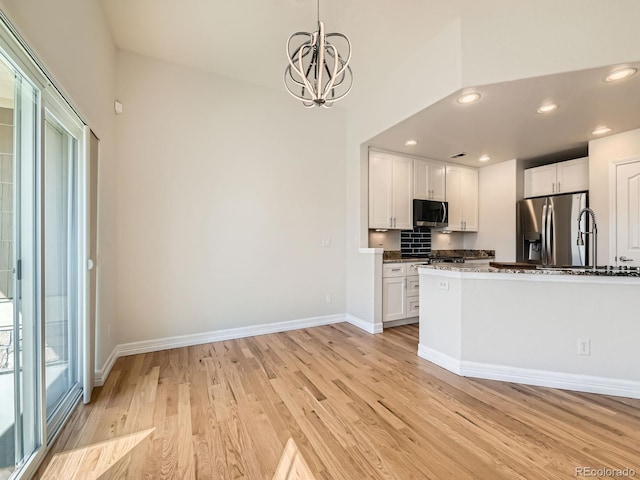 kitchen with baseboards, appliances with stainless steel finishes, light wood-type flooring, and white cabinets