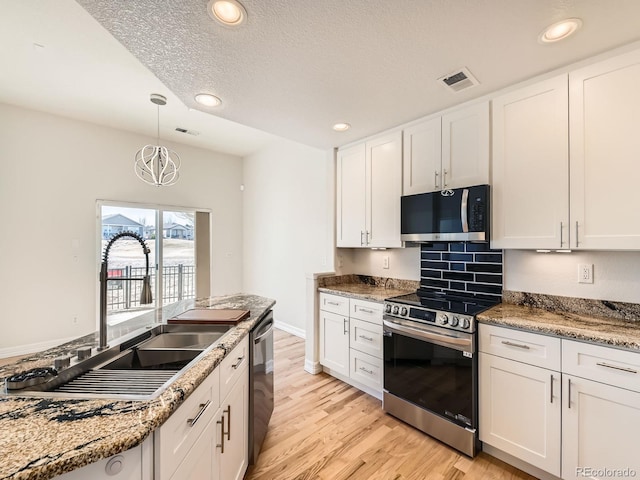 kitchen featuring visible vents, appliances with stainless steel finishes, light wood-type flooring, white cabinetry, and a sink