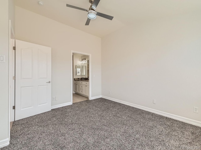 unfurnished bedroom featuring carpet floors, ensuite bath, baseboards, and a ceiling fan