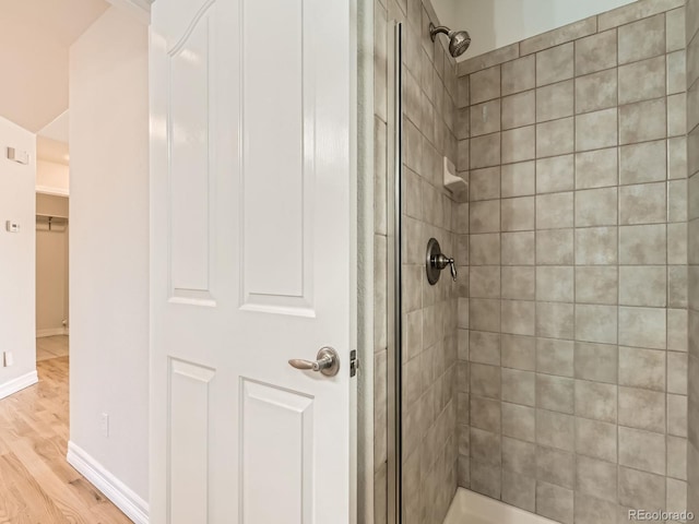 full bath with a stall shower, wood finished floors, and baseboards