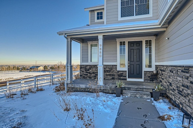 snow covered property entrance featuring a porch