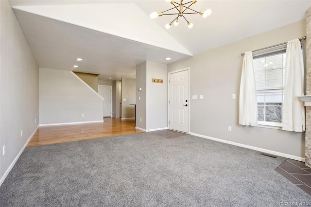 unfurnished living room featuring carpet, baseboards, visible vents, lofted ceiling, and a chandelier