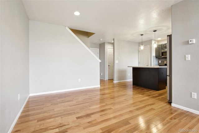 unfurnished living room with recessed lighting, baseboards, and light wood-style floors