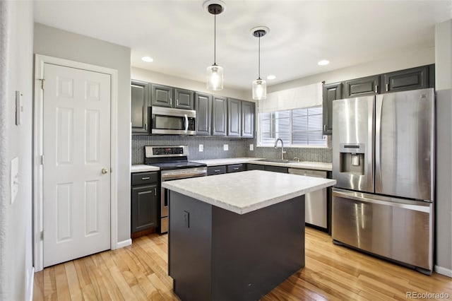 kitchen with a sink, light wood-style floors, appliances with stainless steel finishes, and light countertops