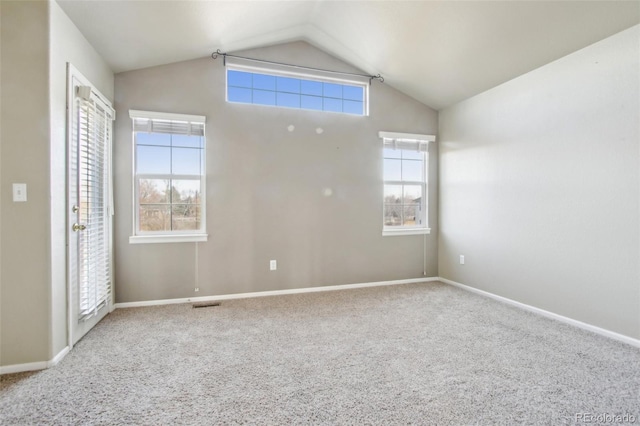 carpeted spare room with baseboards, visible vents, lofted ceiling, and a healthy amount of sunlight