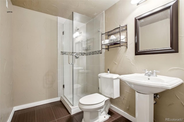 bathroom with a shower stall, toilet, and baseboards