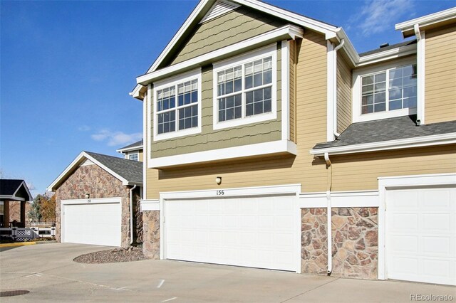 view of front of home featuring stone siding, driveway, and an attached garage