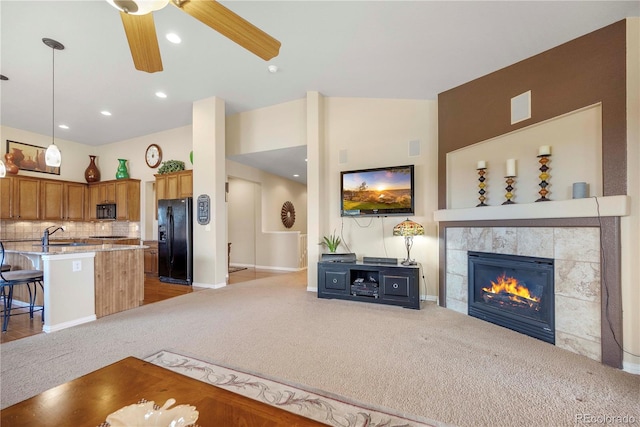 carpeted living room featuring ceiling fan, sink, and a tile fireplace